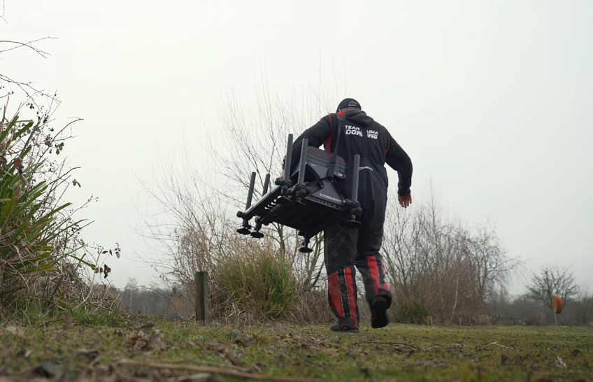 Man carrying the Tournament 800 fishing seat box from Diawa
